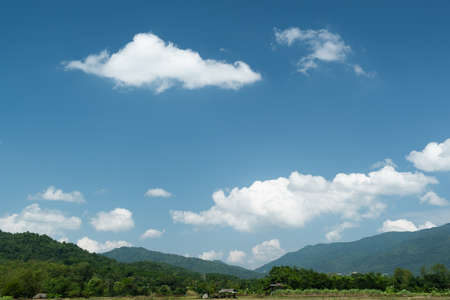 The white clouds have a quaint and rural shape. The sky is cloudy and blue.の写真素材
