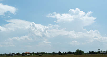 The white clouds have a quaint and rural shape. The sky is cloudy and blue.の写真素材