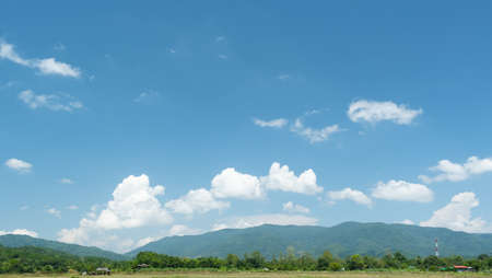 The white clouds have a quaint and rural shape. The sky is cloudy and blue.の写真素材