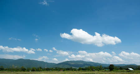 The white clouds have a quaint and rural shape. The sky is cloudy and blue.の写真素材