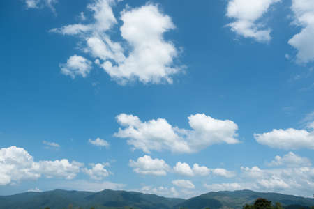 The white clouds have a strange shape and moutain.The sky and the open space have mountains below.Clouds floating above the mountainsの写真素材