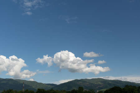 The white clouds have a strange shape and moutain.The sky and the open space have mountains below.Clouds floating above the mountainsの写真素材