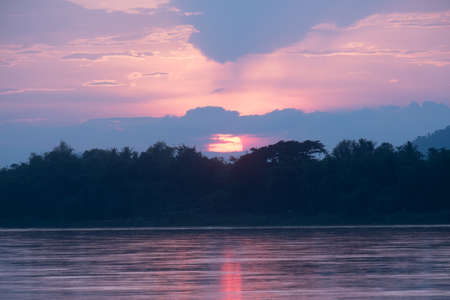 Evening sky behind the mountains.In front of the river.The sky at sunset is about to set off the horizon.の写真素材