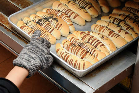 Hand pull out baked bread on tray. The hand wear gloves.の写真素材