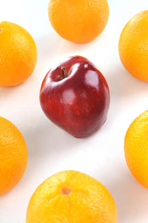 Red apple in the middle of orange isolated white backgroundの写真素材