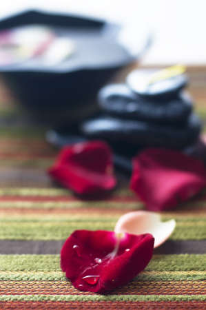 Drop of water on red flower petals isolated blur colorful petals, black rock and bowls