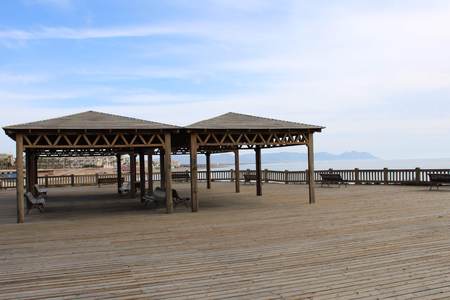 Wooden esplanade with gazebo and benches on the beachの写真素材