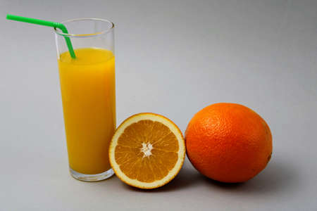 Refreshing glass of orange juice and split fruitの写真素材