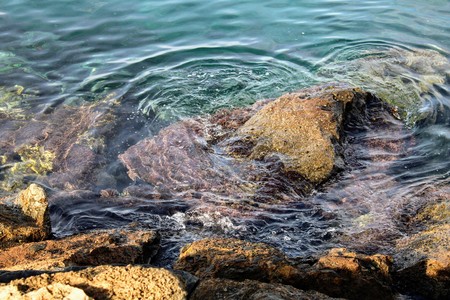 Rocky mountain on the seashore and peaks of rocks coming out of waterの写真素材