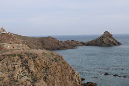 Rocky mountain on the seashore and peaks of rocks coming out of waterの写真素材