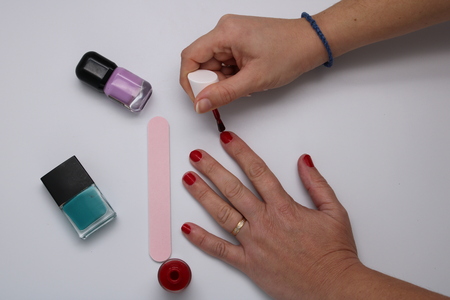 Manicurist painting nails on white table with red enamelの写真素材