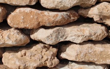 Wall of brown stones stacked and glued with cementの写真素材