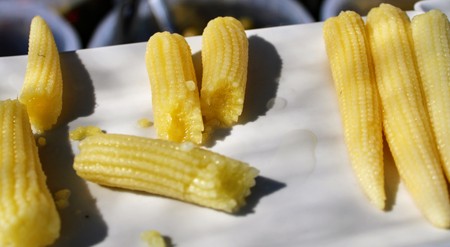 White plate with small baby yellow pickled corn at market stallの写真素材