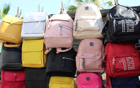 Leather and fabric bags of different colors exhibited in the market