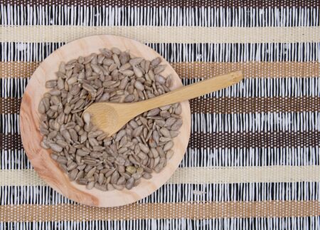 Round wooden board with peeled sunflower seeds and wooden spoonの写真素材