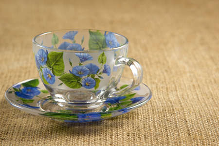 glass mug on a saucer for tea with blue flowersの写真素材