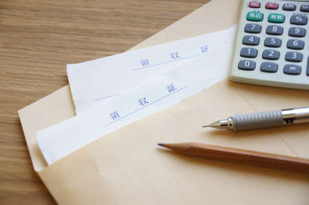 A receipt, a calculator and a pen in an envelopeの写真素材