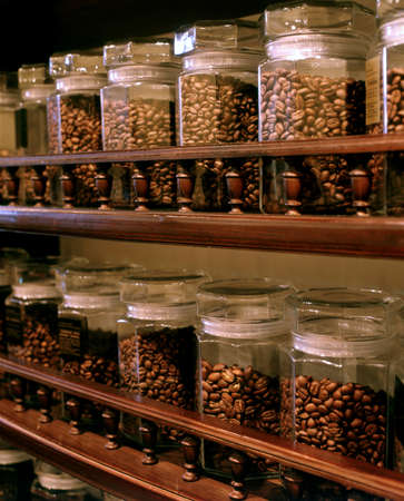 Different coffee sorts are present on grocery shelves. Coffee beans are placed into the glass bottles.の写真素材