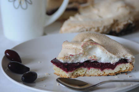 This is a cake stuffed with cornel-berry jam and covered with meringue. The tart is situated on white plate and decorated with berries.の写真素材