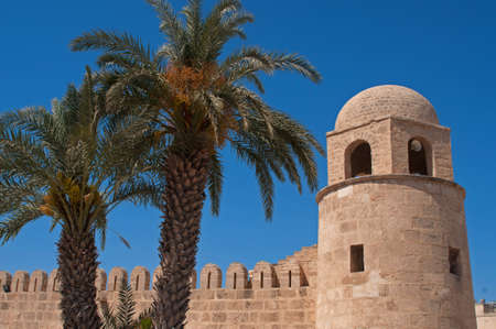 Medina and date palms against the blue sky background are the trademark of Tunisia. The Medina of Sousse constitutes an outstanding example of Arabo-Muslim and Mediterranean architecture.の写真素材
