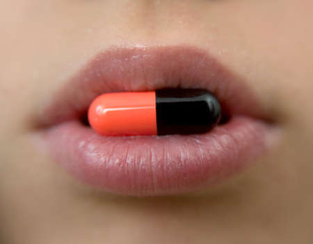 This is a close-up of multicolored pill in the mouth.の写真素材
