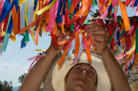  Young	woman makes a wish near multicolored wish tree (Crimea).  According to tradition the people tie ribbon on the tree and make a wish.の写真素材