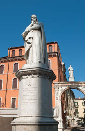 This is a marble Dante monument in Verona (Italy). Blue sky and old buildings are in the background.のeditorial素材