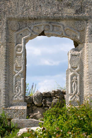 Mangup kale architecture (Crimea): old gate and bright green flora. The entrance to  nonexistent...
