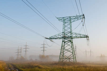 Electricity transmission line  in morning mist. Electric constructions  stand on grassland.の写真素材