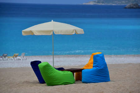 Bright multicolored seats and sunshade are situated on the beach. Blue sea is in the background. This is a sand equipped beach.の写真素材
