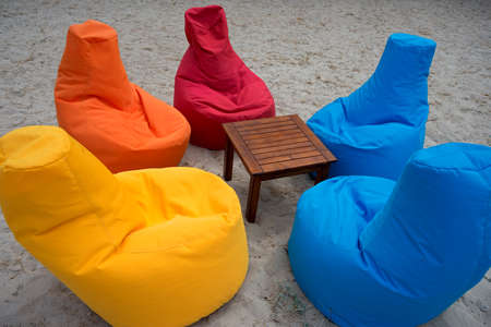 Place for relax on the sand beach. Multicolored seats looking like an armchair surround little wood table.の写真素材