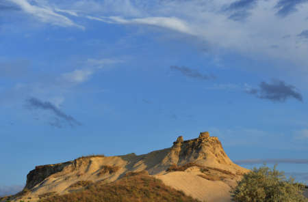Sunlit mount against blue sky. Green bushes, grass are in the foreground. Place - Cappadocia Turkey.の写真素材