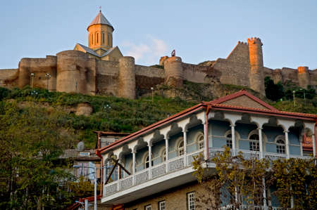 Tbilisi. Old traditional georgian house against Narikala fortress background.
