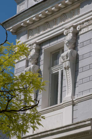Old house exterior view Duvanovskaya street, Yevpatoria. Building is decorated with woman heads sculptures.  Bright green green branch soups composition.の写真素材