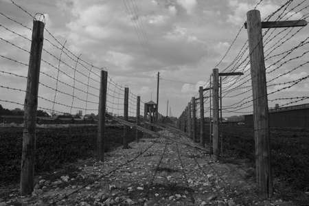 Two rows of barb-wire fence in  Majdanek concentration camp. Black-and-white color range emphasizes morose of buildings.のeditorial素材