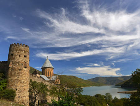 Medieval Ananuri complex: castle and church against azure lake and mountains landscape background. The sky is also beauty - bright blue with different clouds.のeditorial素材