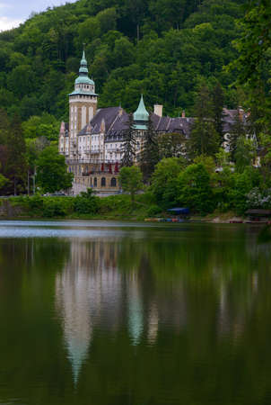 Northern front of Lillafured palace (Miskolc, Hungary). Lake Hamori in foreground, mountains covered...