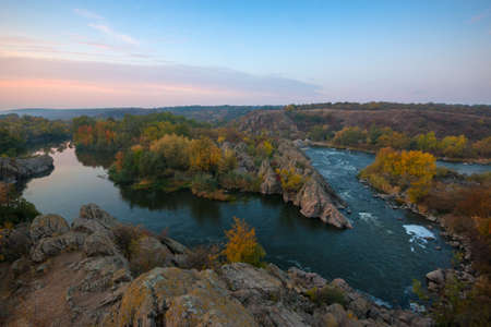 Sunrise scene with yellow trees. Rocks in foregrpund. Top view of Integral rift on Southern Bug river.の写真素材