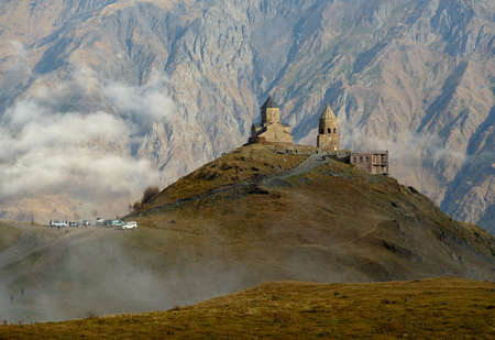 Gergeti Trinity Church against mountain background. White clouds are goods for composition. Daytime...