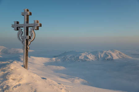 Frosted cross under mountains and cloudsの写真素材
