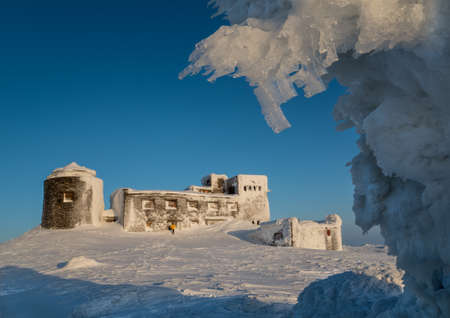 Frosted old Polish observatory on Pop Ivan Mount (Ukraine) against blue sky background. Little man...