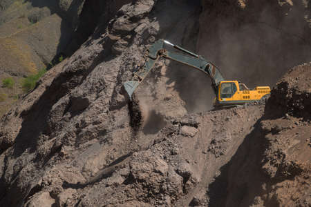 Yellow excavator working in mountains.の写真素材