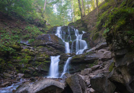 Shypit waterfall among green trees and plants. Sunlit autumn forest in background.の写真素材