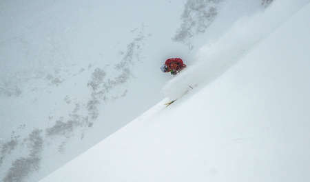 Freeride under snow fall. Skier dressed in red cloth.