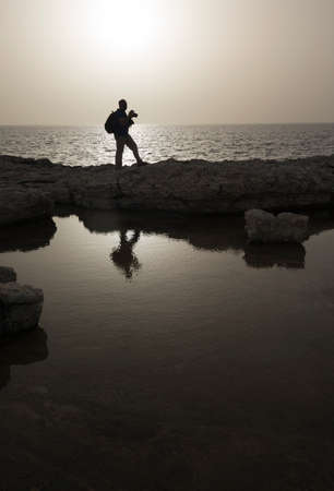 Photographer silhouette against sea landscape. Sunset time. Monochromatic image.の写真素材