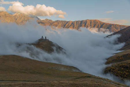 Gergeti Trinity Church (Georgia) surrounded with mountains and clouds.