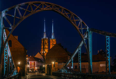 Night scene in Wroclaw. Illuminated old buildings and cathedral. Arch of bridge in foreground.の写真素材