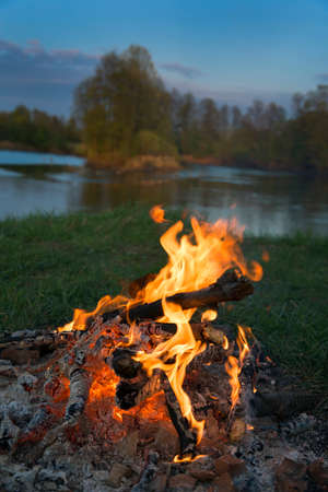 Fire (campfire) against landscape with river background.の写真素材