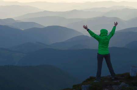 Woman with outstretched hands in mountains. Woman looks at mountains ranges. She is happy.の写真素材