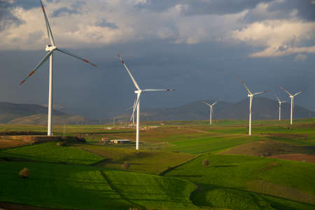 Wind power station against beautiful rural landscape. White wind power plants stand out well against the backdrop of thunderclouds.のeditorial素材